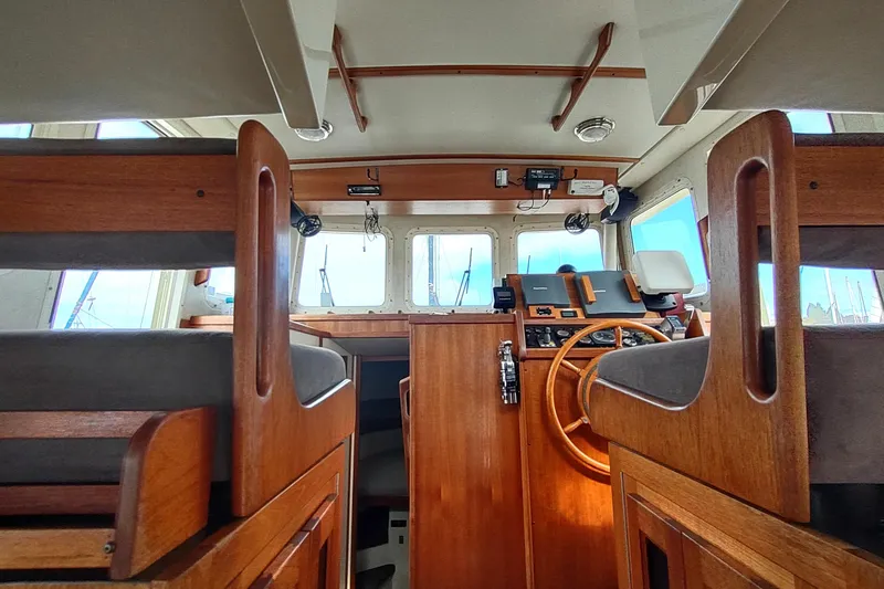 Bernardi Yacht Photos Pics 2004 Nordic Tug 32 interior with wooden helm and seating, showcasing nautical design.