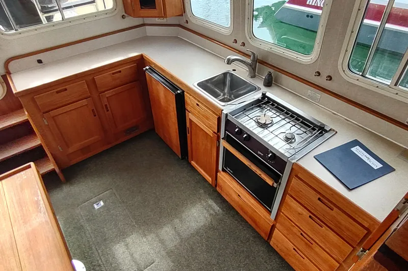 Bernardi Yacht Photos Pics 2004 Nordic Tug 32 interior kitchen with wooden cabinets, stove, and sink.