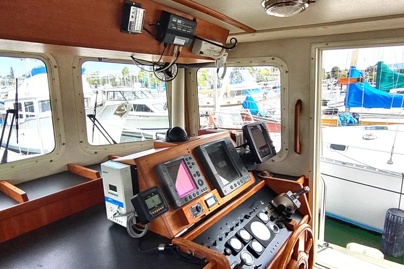 Bernardi Yacht Photos Pics Interior helm of 2004 Nordic Tug 32 with navigation equipment and marina view.