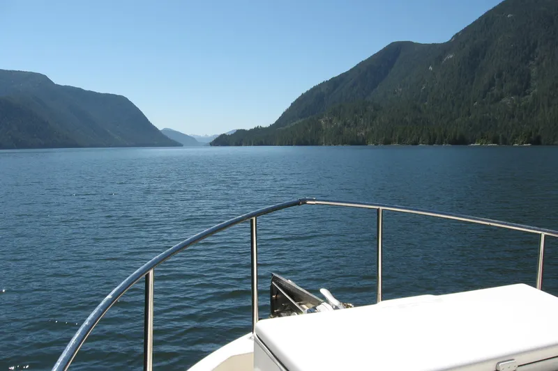 Bernardi Yacht Photos Pics Nordic Tug 32 (2004) cruising through scenic mountain lake with clear blue skies.