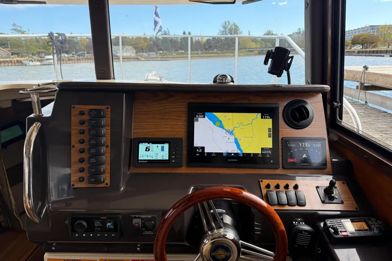  Yacht Photos Pics 2025 Ranger Tugs R-27 helm with navigation screens and controls, docked by a scenic waterfront.