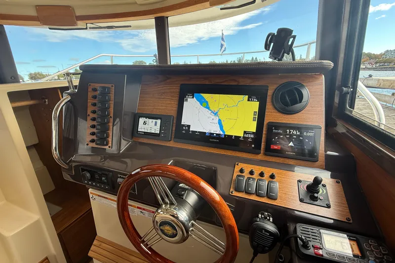  Yacht Photos Pics 2025 Ranger Tugs R-27 helm with navigation screens and wooden steering wheel.