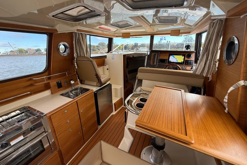  Yacht Photos Pics Interior of 2025 Ranger Tugs R-27 boat with wood finish, kitchenette, and navigation area.