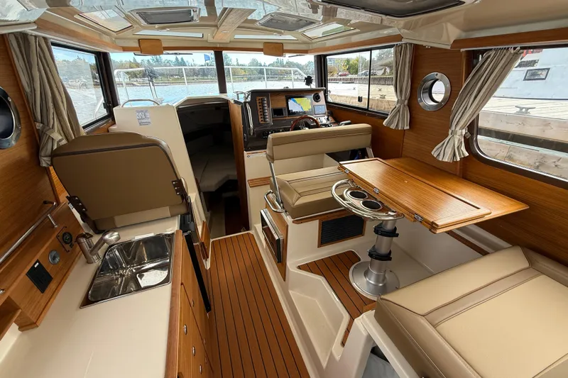  Yacht Photos Pics 2025 Ranger Tugs R-27 interior with wood accents, dining area, and navigation equipment.