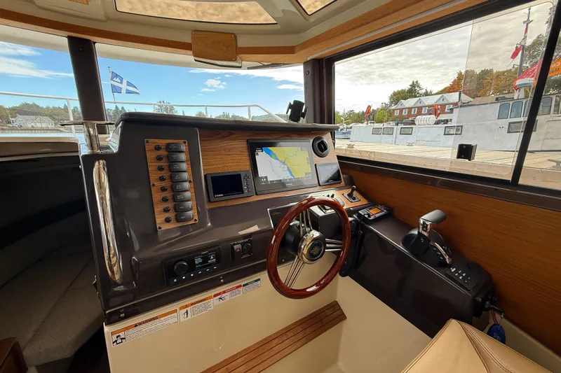  Yacht Photos Pics 2025 Ranger Tugs R-27 helm with navigation system and wooden steering wheel.