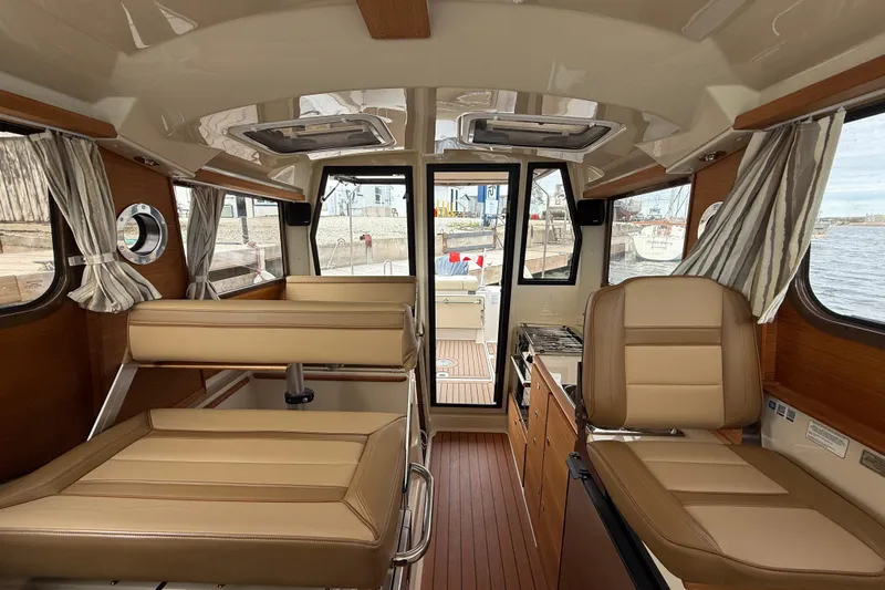  Yacht Photos Pics 2025 Ranger Tugs R-27 interior with tan seating, wood accents, and waterfront view.