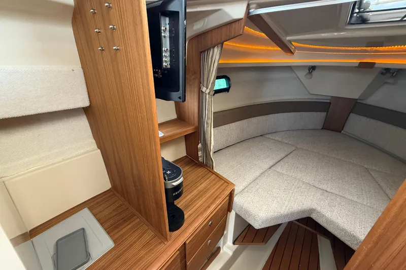 Yacht Photos Pics 2025 Ranger Tugs R-27 cabin interior with cozy seating and wooden cabinetry.