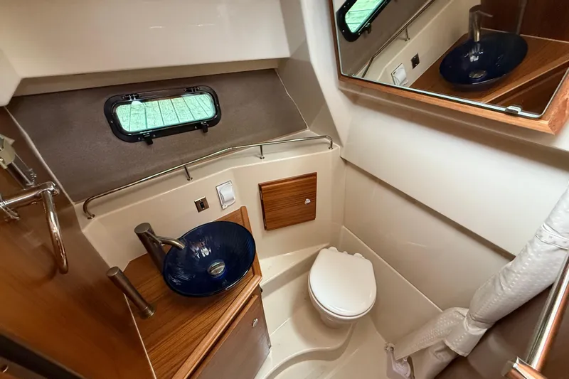  Yacht Photos Pics 2025 Ranger Tugs R-27 boat bathroom with modern sink, toilet, and mirror.