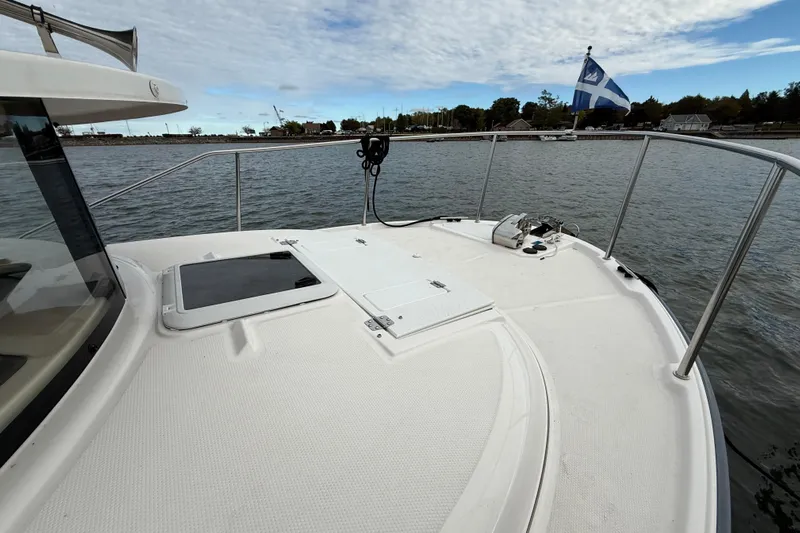  Yacht Photos Pics 2025 Ranger Tugs R-27 boat deck with railing, hatch, and flag on calm water.