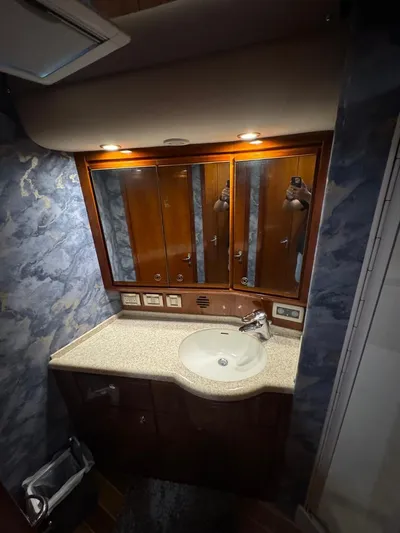 Spill Yacht Photos Pics 2007 Bertram 510 Convertible yacht bathroom with marble walls and wooden cabinetry.