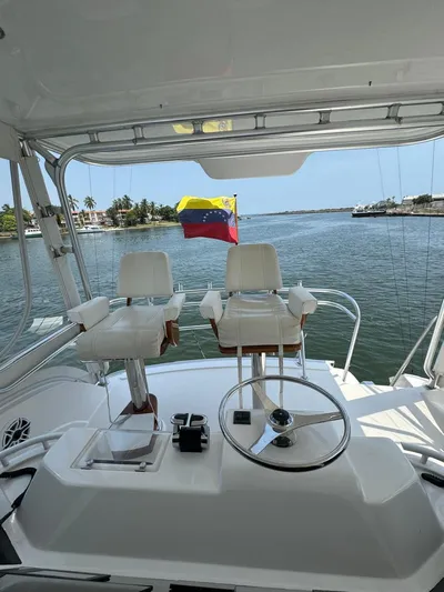 Spill Yacht Photos Pics 2007 Bertram 510 Convertible yacht helm with Venezuelan flag on calm waters.