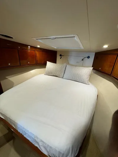 Spill Yacht Photos Pics 2007 Bertram 510 Convertible cabin with bed and wooden storage cabinets.