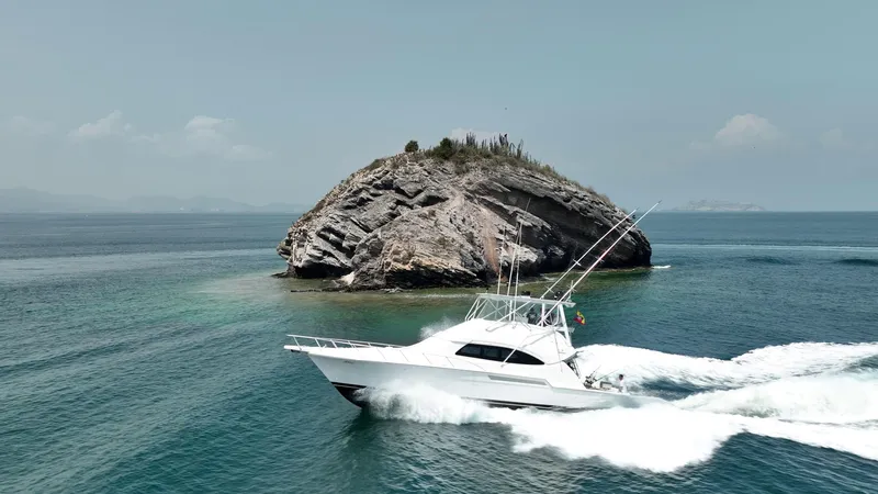 Spill Yacht Photos Pics 2007 Bertram 510 Convertible yacht cruising near a rocky island.