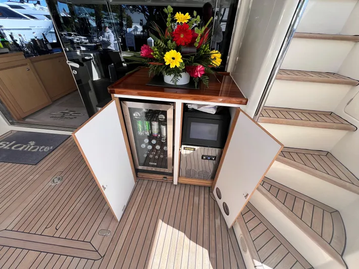 Slainte III Yacht Photos Pics Custom Line Navetta 2013 yacht interior with open cabinet, flowers, and wooden flooring.