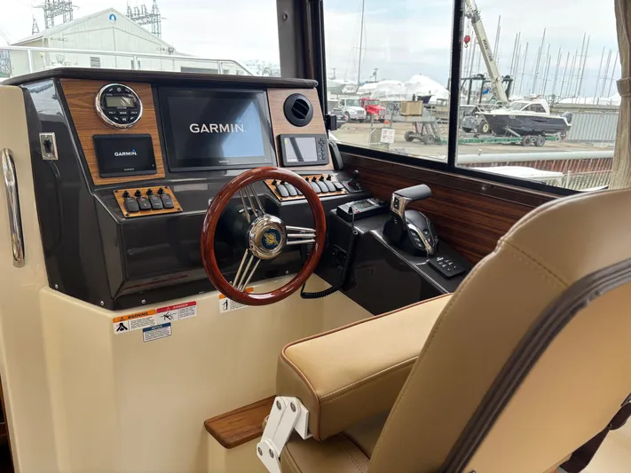  Yacht Photos Pics 2025 Ranger Tugs R-25 helm with Garmin navigation, wooden accents, and comfortable seating.