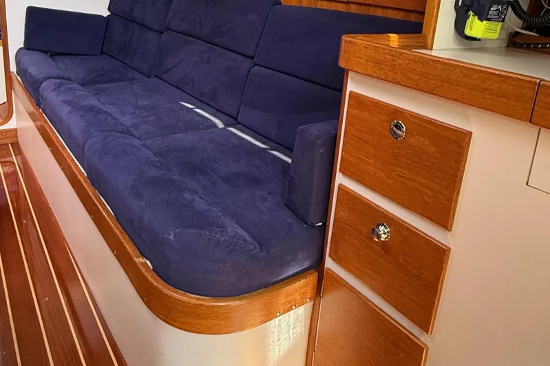 Microdarcy(ud) Yacht Photos Pics Interior of 2005 J Boats J/124, featuring a blue cushioned sofa and wooden cabinetry.