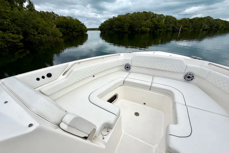  Yacht Photos Pics 2024 Pursuit DC 365 Dual Console boat interior with white seating, surrounded by lush greenery.