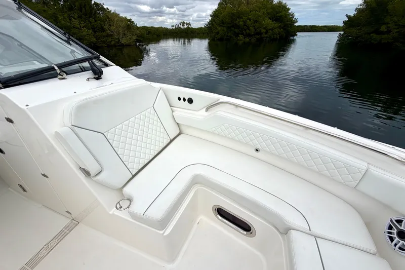  Yacht Photos Pics 2024 Pursuit DC 365 Dual Console boat interior with white seating, near lush waterway.