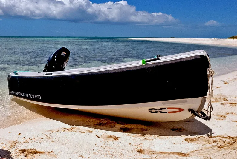 Escapist Yacht Photos Pics A small boat on a sandy beach with clear blue water and sky.