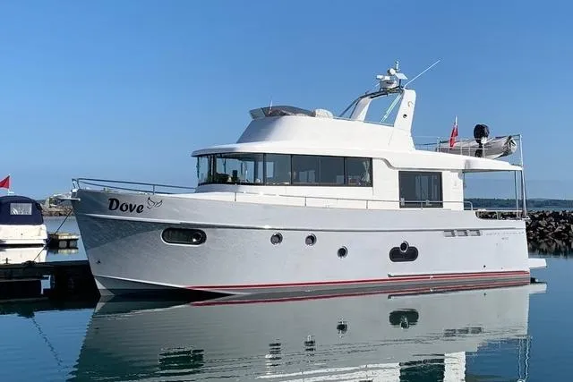 Dove Yacht Photos Pics 2015 Beneteau Swift Trawler 50 yacht docked in calm waters, clear sky background.