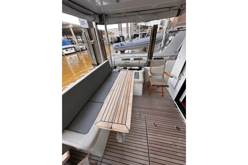 Dove Yacht Photos Pics 2015 Beneteau Swift Trawler 50 deck with seating and wooden table, docked at marina.