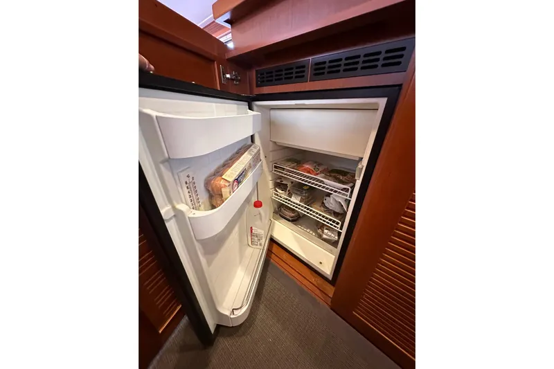 Dove Yacht Photos Pics Open refrigerator inside 2015 Beneteau Swift Trawler 50, stocked with food items.