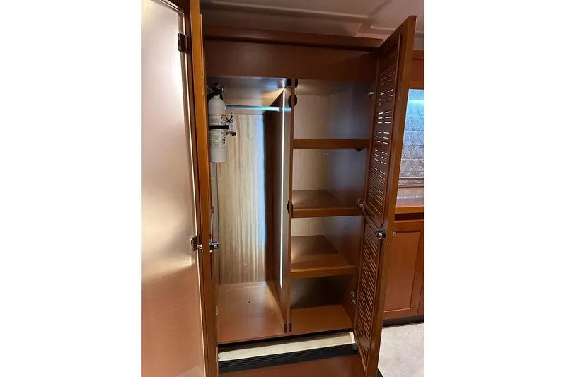 Dove Yacht Photos Pics Interior storage cabinet on 2015 Beneteau Swift Trawler 50 with shelves and fire extinguisher.