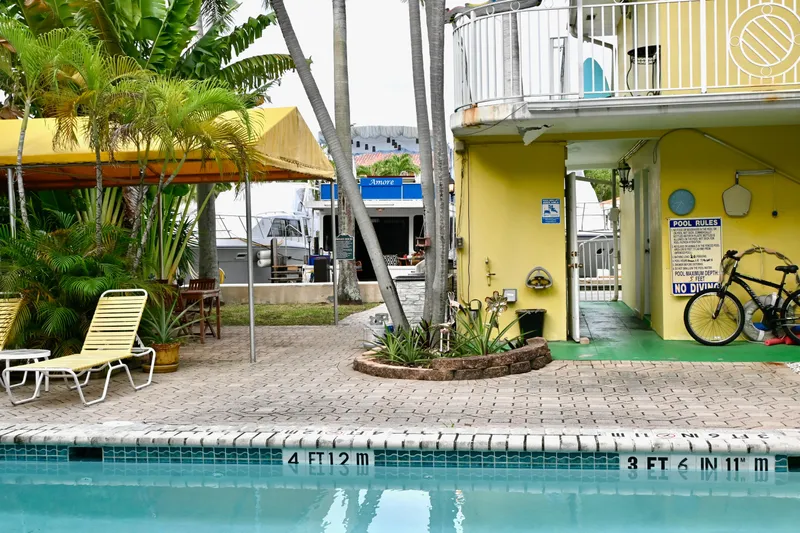 Amore Yacht Photos Pics Poolside view with yellow building, lounge chairs, and a Catamaran Cruisers Aqua Cruiser 44 in the background.