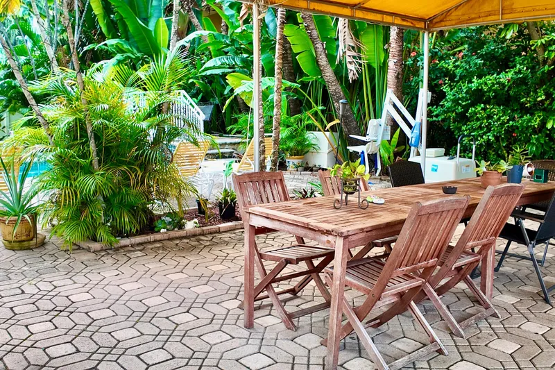 Amore Yacht Photos Pics Outdoor patio with wooden furniture, lush greenery, and a poolside view.