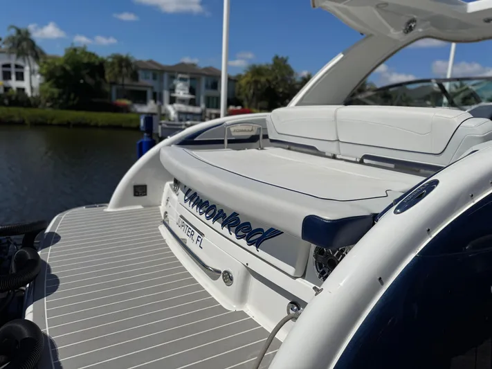 Uncorked Yacht Photos Pics 2023 Formula 350 Crossover Bowrider docked by waterfront homes under blue sky.