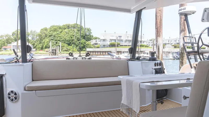 Nohea Yacht Photos Pics Interior of 2022 Custom Current Marine 46 yacht with seating and table, docked by the water.