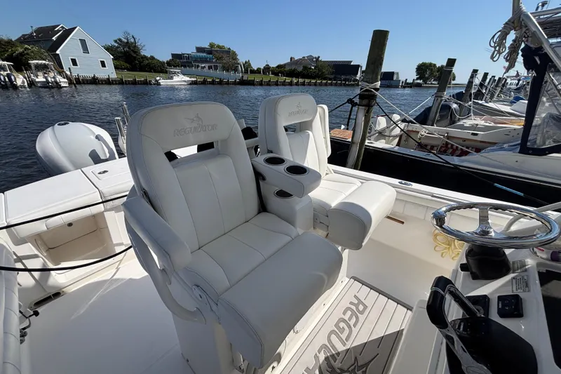  Yacht Photos Pics 2017 Regulator 28 boat interior with white seating and steering wheel, docked by waterfront homes.