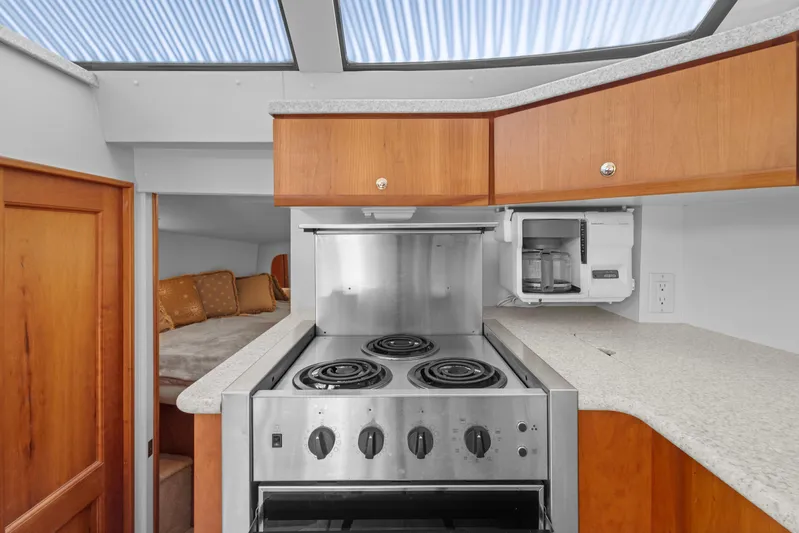  Yacht Photos Pics 2000 Silverton 392 Motor Yacht kitchen with stove, wooden cabinets, and cozy sleeping area.