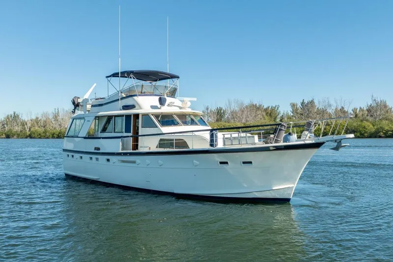 Even Keel Yacht Photos Pics 1985 Hatteras 53 Motor Yacht cruising on a serene waterway under clear blue skies.