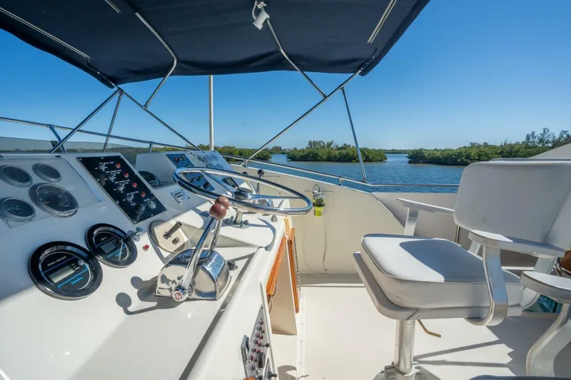 Even Keel Yacht Photos Pics 1985 Hatteras 53 Motor Yacht helm with controls, gauges, and seating under a blue canopy.
