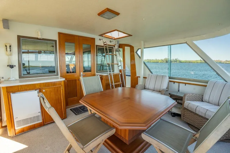 Even Keel Yacht Photos Pics 1985 Hatteras 53 Motor Yacht interior with dining area, wooden table, and lake view.