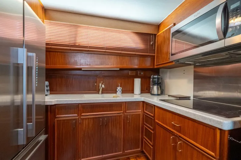 Even Keel Yacht Photos Pics 1985 Hatteras 53 Motor Yacht kitchen with wood cabinetry, modern appliances, and sleek countertops.