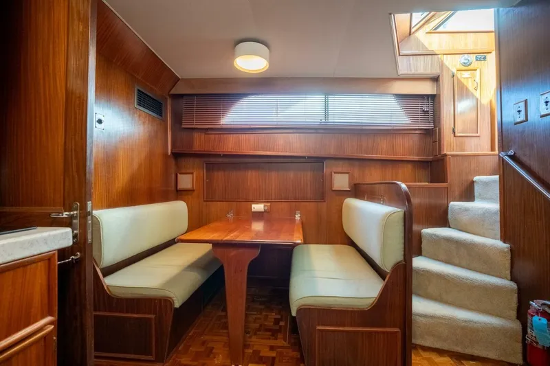 Even Keel Yacht Photos Pics Interior of 1985 Hatteras 53 Motor Yacht with wood paneling and cozy dining area.