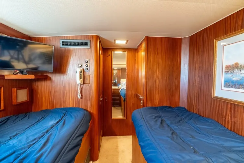 Even Keel Yacht Photos Pics 1985 Hatteras 53 Motor Yacht cabin with twin beds, wood paneling, and wall-mounted TV.