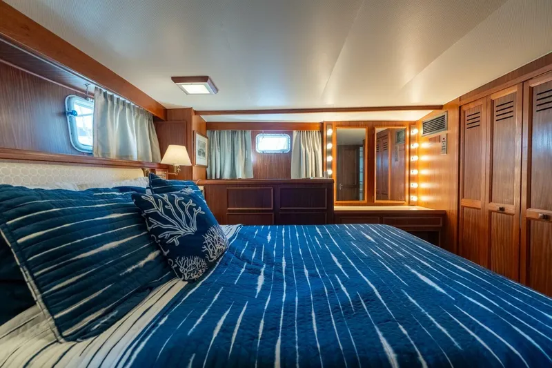 Even Keel Yacht Photos Pics Luxurious bedroom interior of 1985 Hatteras 53 Motor Yacht with blue bedding and wood accents.