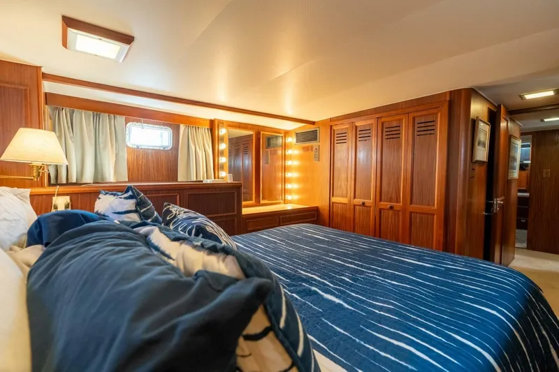 Even Keel Yacht Photos Pics Luxurious bedroom in 1985 Hatteras 53 Motor Yacht with wood paneling and blue bedding.