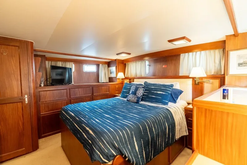 Even Keel Yacht Photos Pics Luxurious cabin interior of 1985 Hatteras 53 Motor Yacht with wood paneling and cozy bedding.