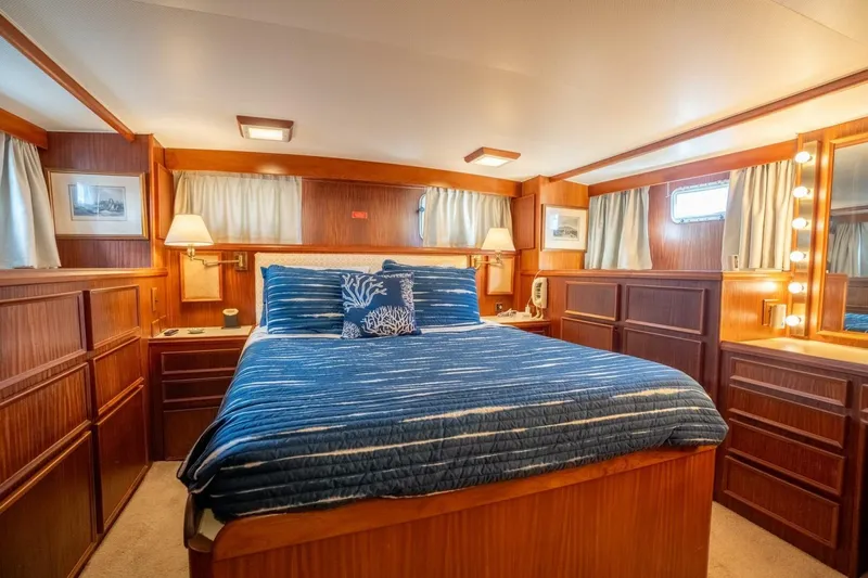 Even Keel Yacht Photos Pics Luxurious bedroom interior of 1985 Hatteras 53 Motor Yacht with wood paneling and blue bedding.