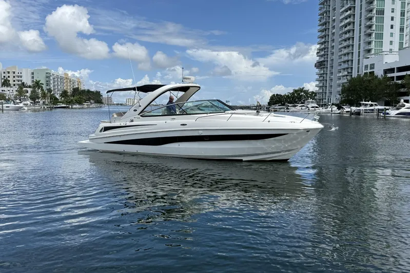  Yacht Photos Pics 2015 Sea Ray 370 Venture yacht cruising in a marina with modern buildings in the background.