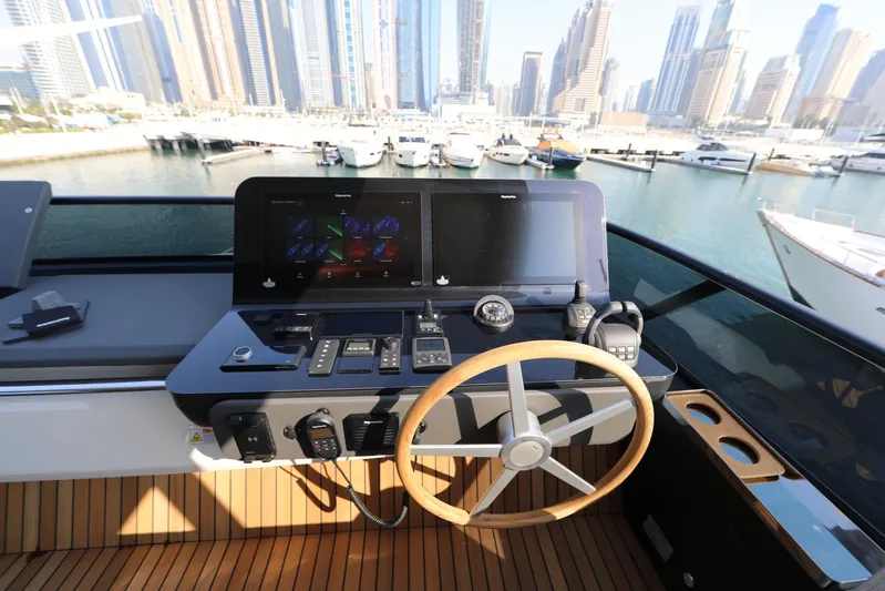  Yacht Photos Pics 2024 Cranchi Sessantasette 67 yacht helm with modern controls, overlooking a marina skyline.