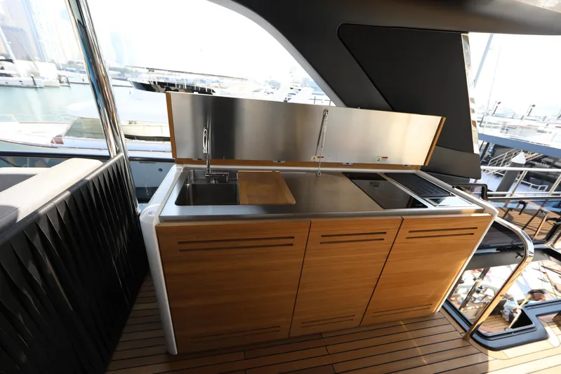  Yacht Photos Pics Outdoor kitchen on 2024 Cranchi Sessantasette 67 yacht with wooden cabinetry and stainless steel surfaces.