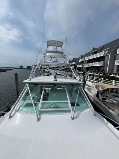 Land Ho Yacht Photos Pics 2007 Cabo 40 Express yacht docked by waterfront homes under a cloudy sky.