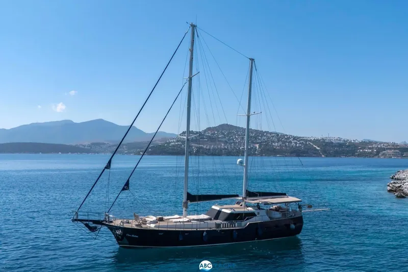 Cİca Sultan Yacht Photos Pics Sailing yacht Ark Yat 24M, 2014 model, on serene blue waters with scenic mountain backdrop.