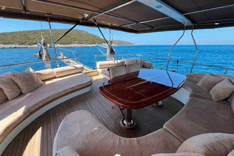Cİca Sultan Yacht Photos Pics Luxurious Ark Yat 24M yacht deck with plush seating, wooden table, and scenic ocean view.