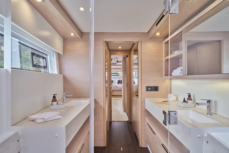  Yacht Photos Pics Luxurious bathroom interior of 2026 Lagoon 51 Owners version yacht, featuring dual sinks and modern design.